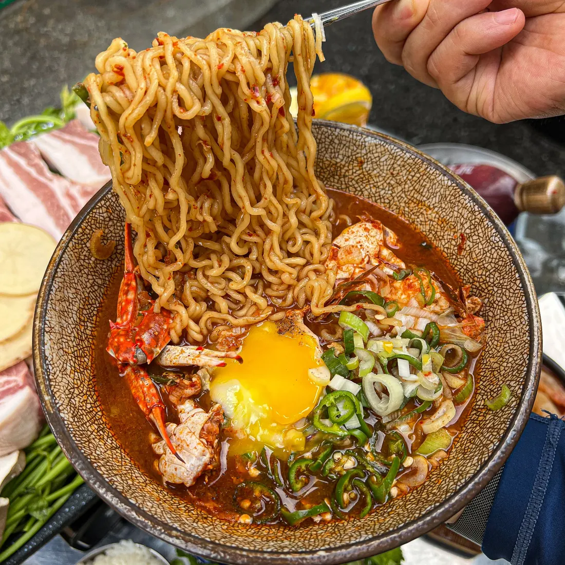 계란을 올리고 면을 건져 올린 꽃게 라면 · 이태원 고기집 · Itaewon Restaurants